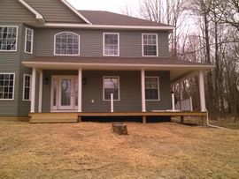 Two-story gray house with a covered front porch and sloped yard